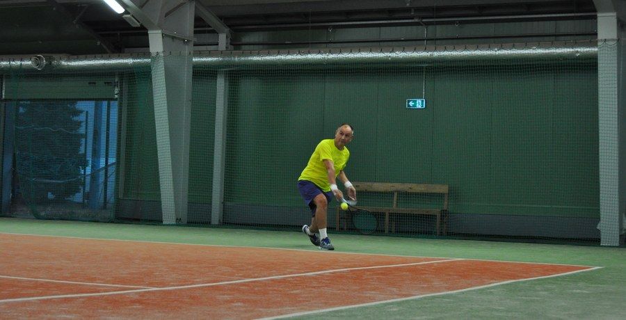Dorosły gracz odbierający piłkę wolejem na korcie BKtenis