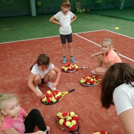 Dzieci z piłkami i rakietami na zajęciach BKtenis
